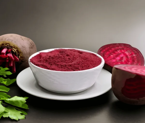 A bowl of beetroot malt powder with fresh beetroots and leaves on a gray background.